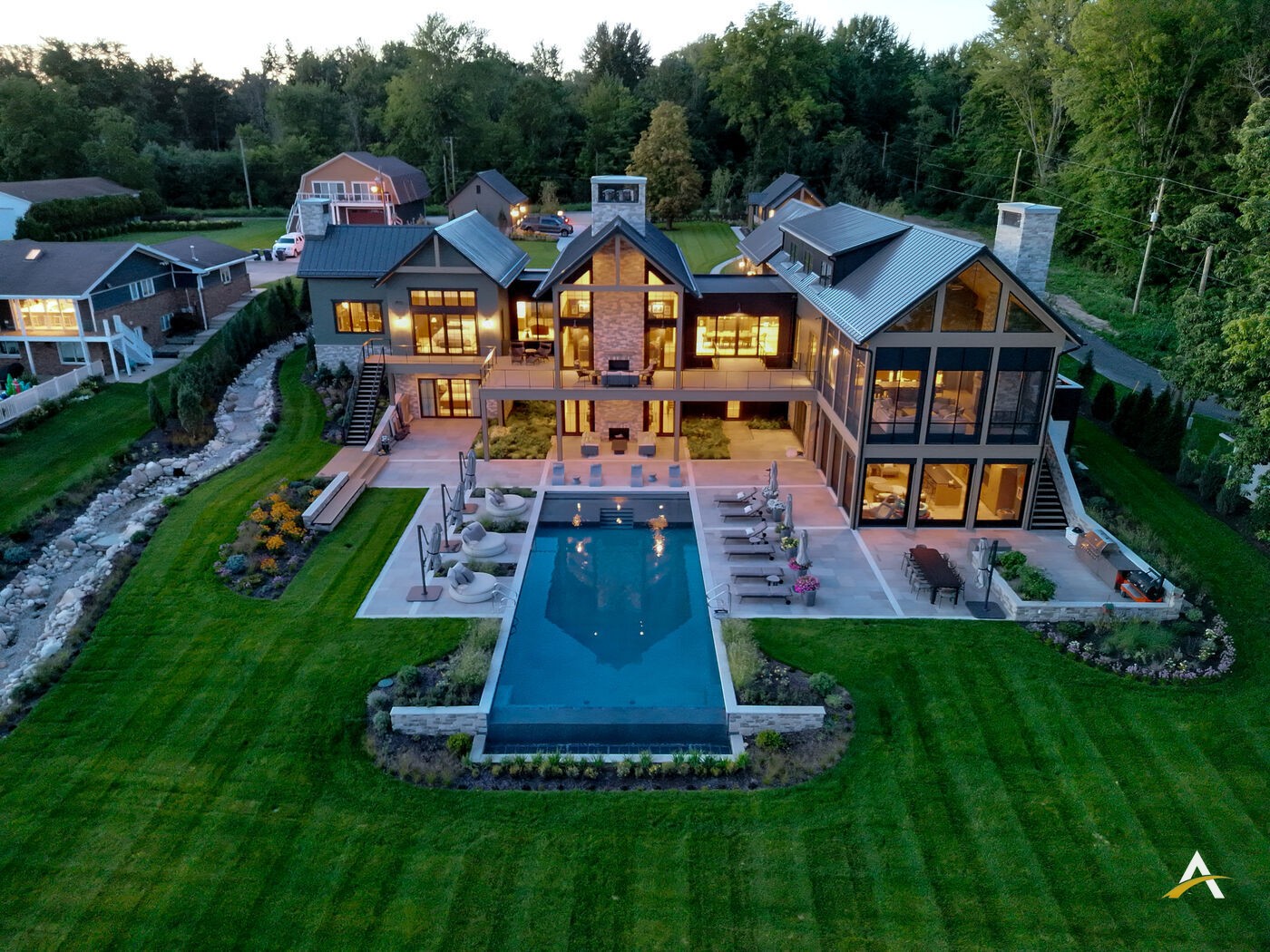 Close blue hour aerial with stone chimney glow and pool reflection