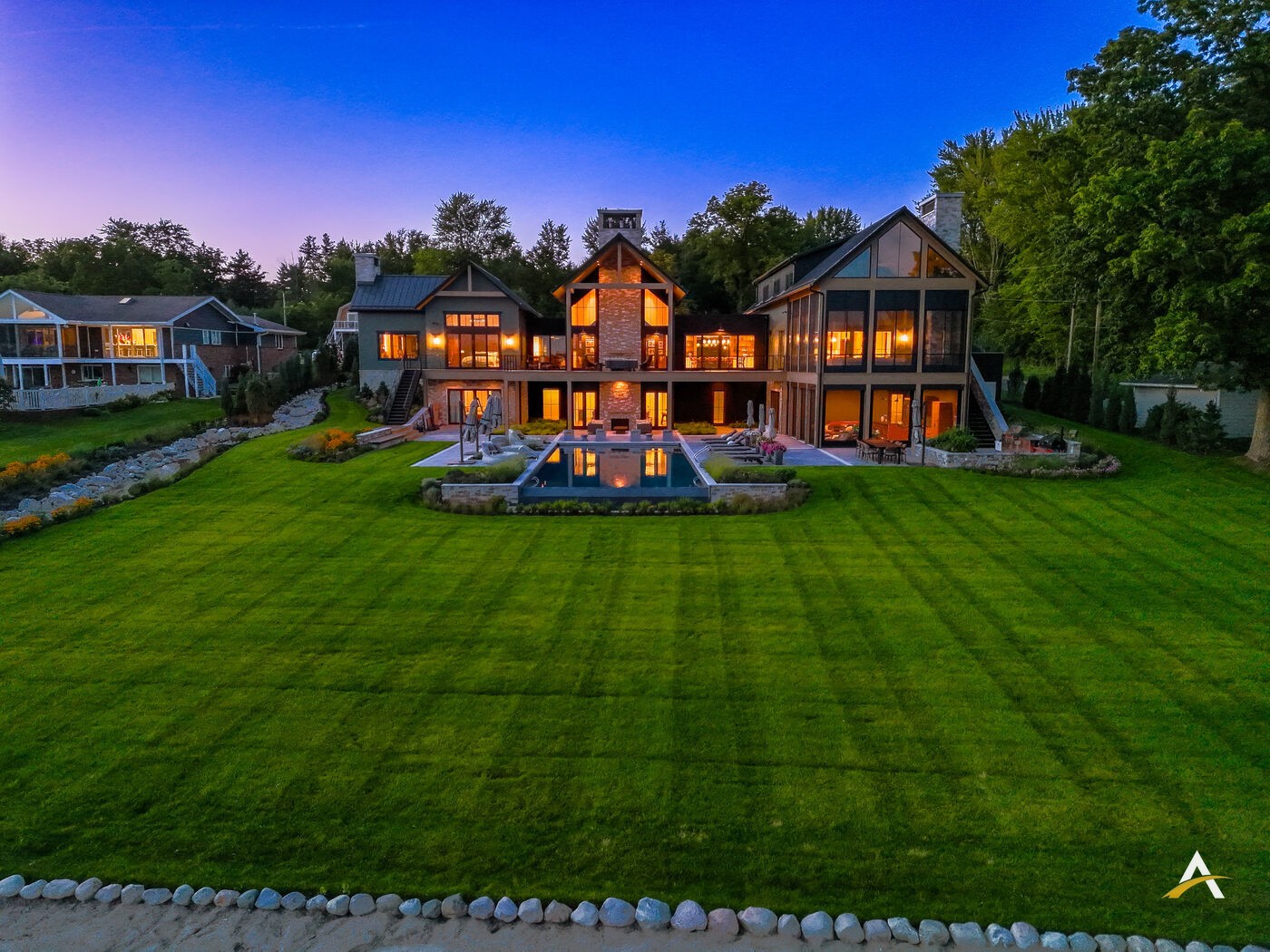 Aerial blue hour portrait of a custom home with warm interior lighting against a deep twilight sky